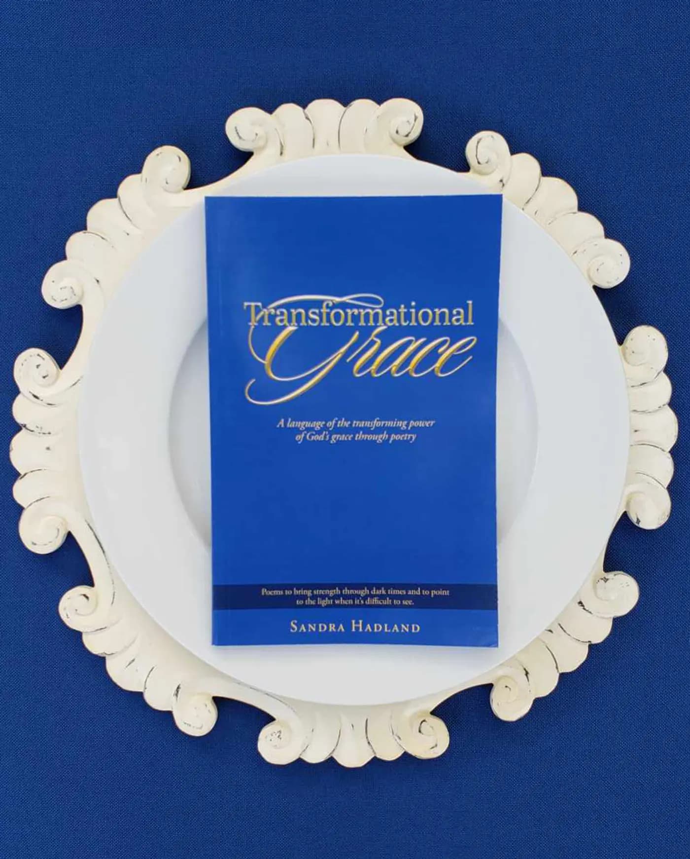The Transformational Grace book on a white plate atop an ornate charger